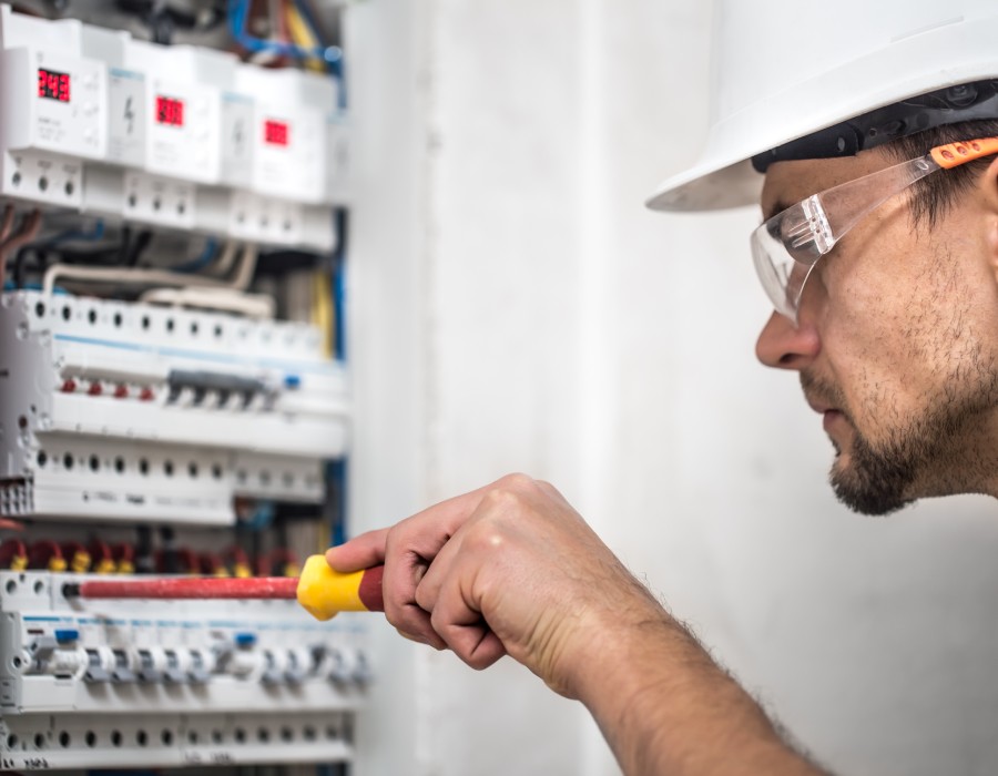 Électricien professionnel réparant un tableau électrique avec un tournevis isolé