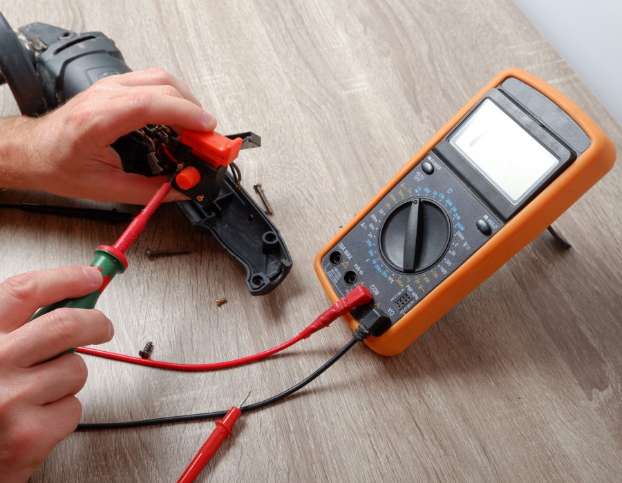 Technicien testant un outil électrique avec un multimètre sur établi