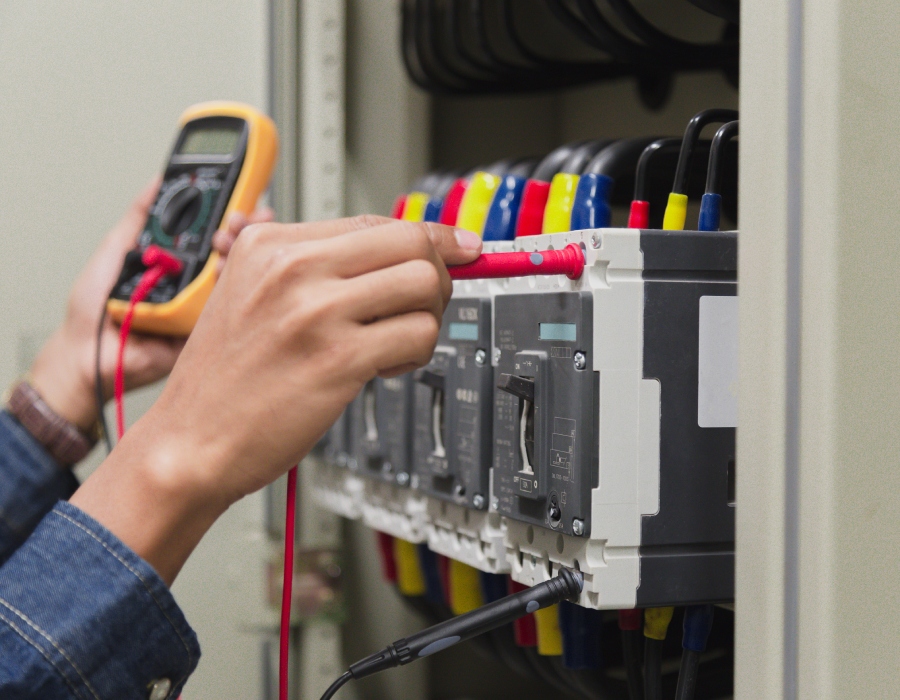Technicien effectuant un contrôle de tension sur un tableau électrique industriel