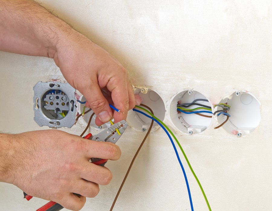 Électricien réalisant le raccordement des fils dans des boîtes murales